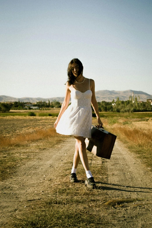 a woman is walking down a dirt road