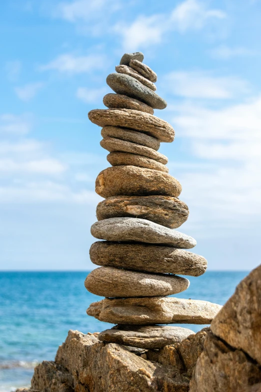 stacked stones on beach near ocean under blue sky