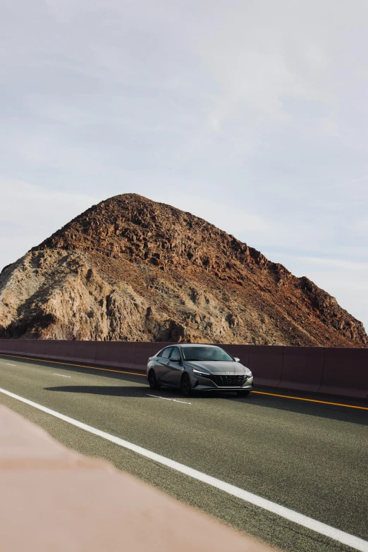 a car is driving on the highway by a big mountain