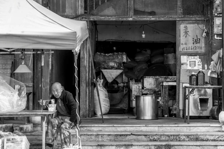 a person sits in front of a shop on the sidewalk