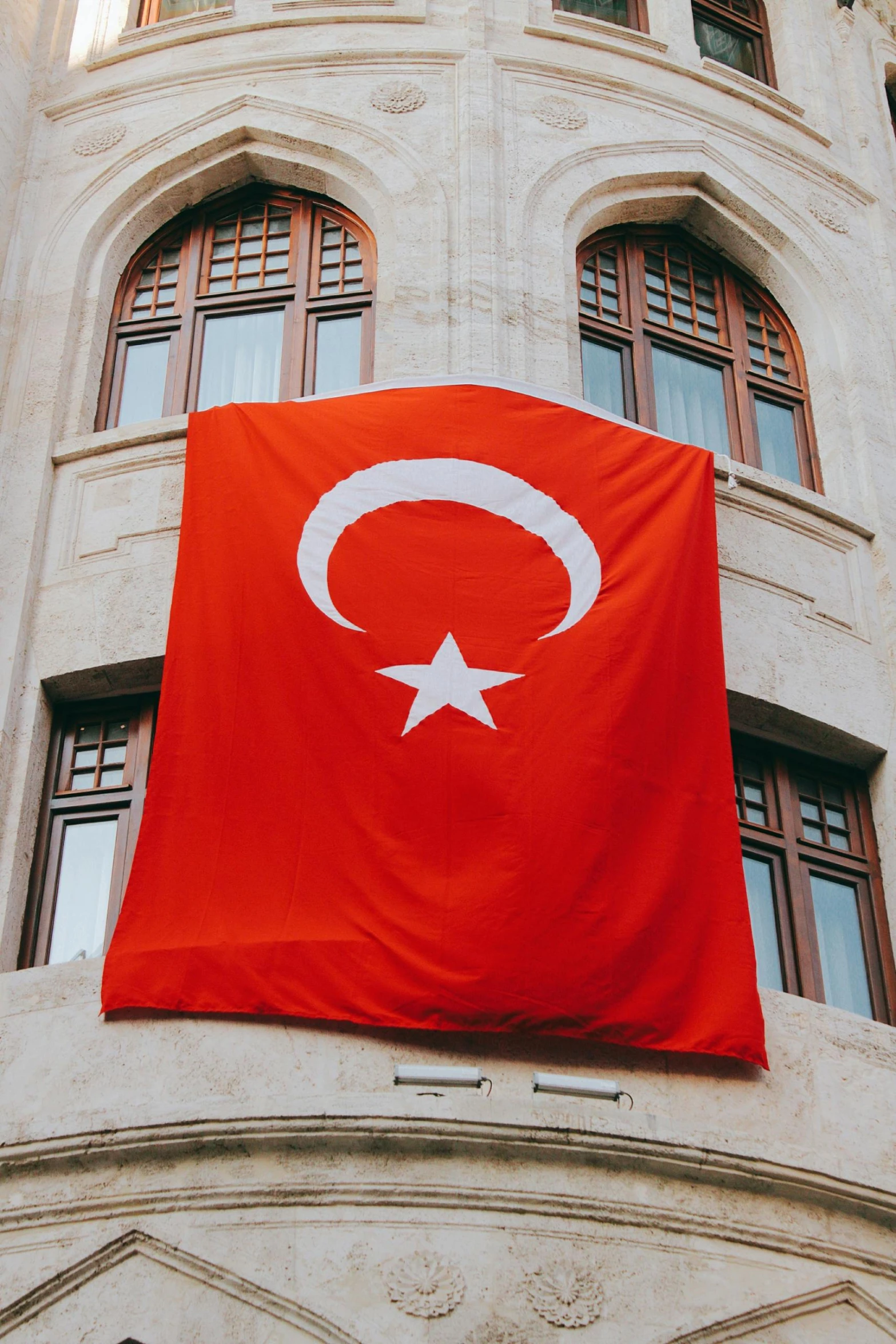 a large red turkish flag hanging from the side of a building