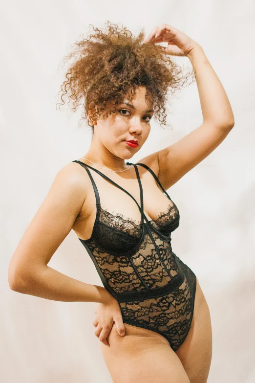 a woman with her arm around her neck posing in lingerie