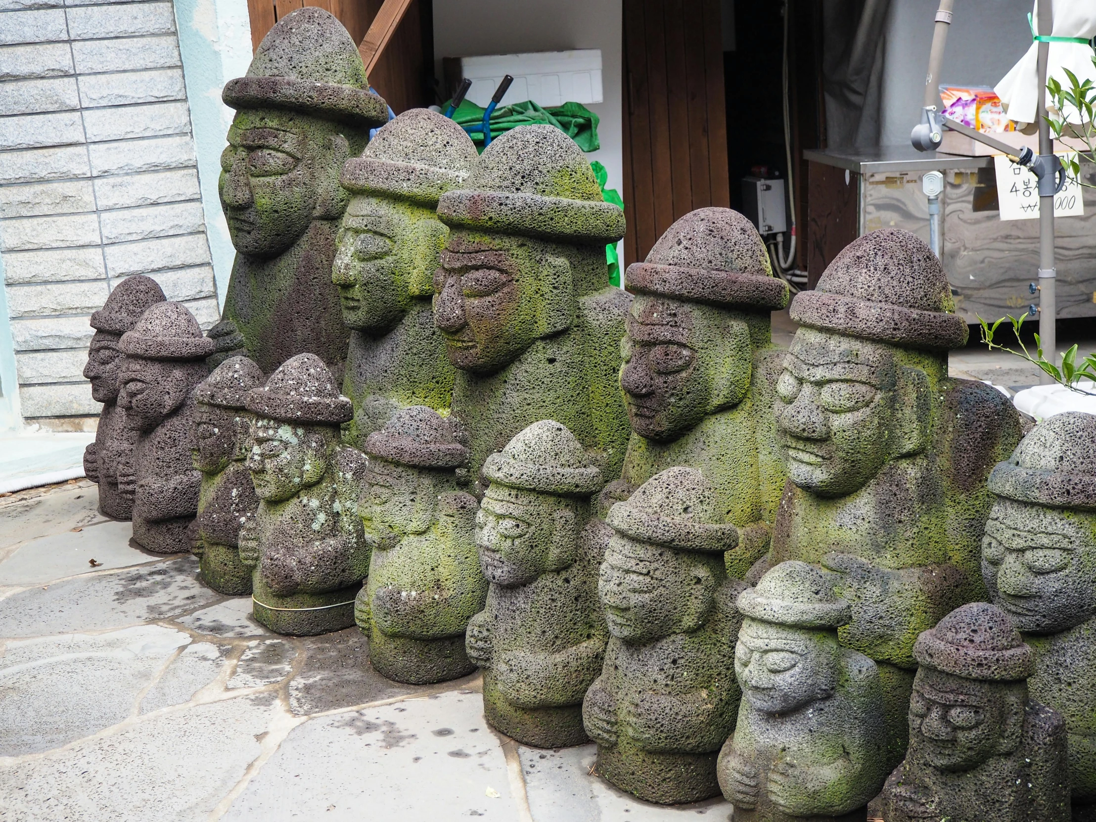 a row of green statues in the shape of buddha faces