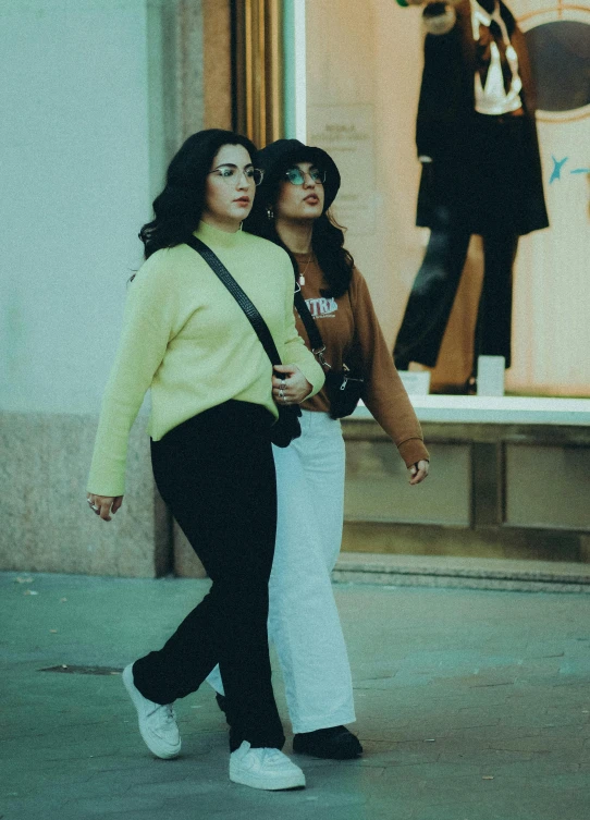 two girls are walking past an open building