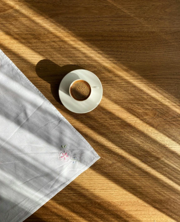 the sun shines through a window onto a table with a cup and saucer