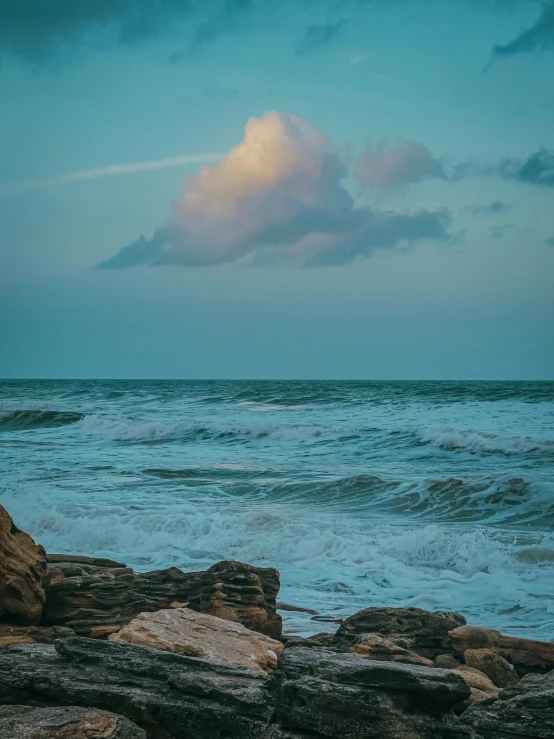 the person is standing alone on the rocks near the ocean