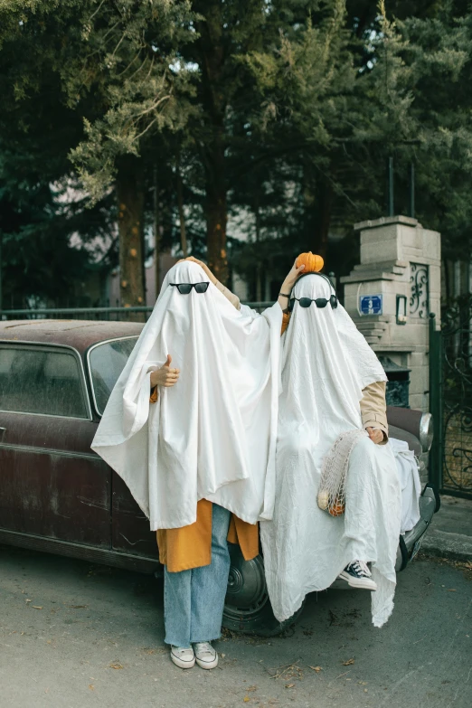 two people wrapped up in white clothes with a brown truck behind them