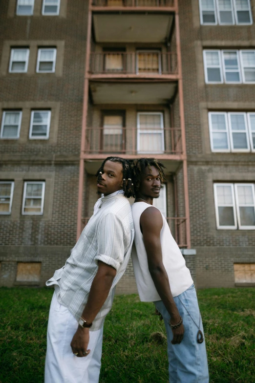 two black people standing near an apartment building