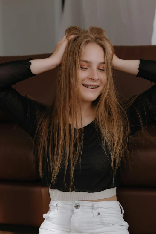 a woman sitting on top of a brown couch with her hands behind her head