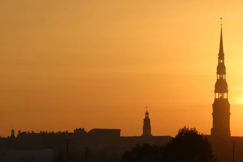 the silhouettes of buildings and a clock tower at sunset