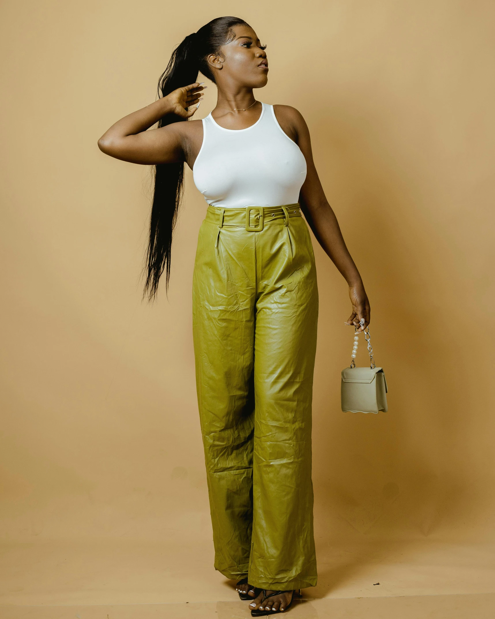 an african american woman in green wide leg pants standing on a brown background