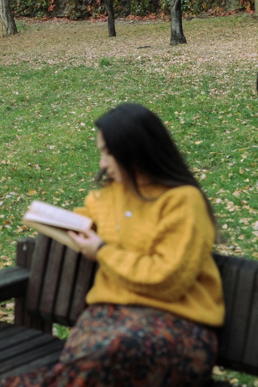 a woman sits on a park bench with an umbrella