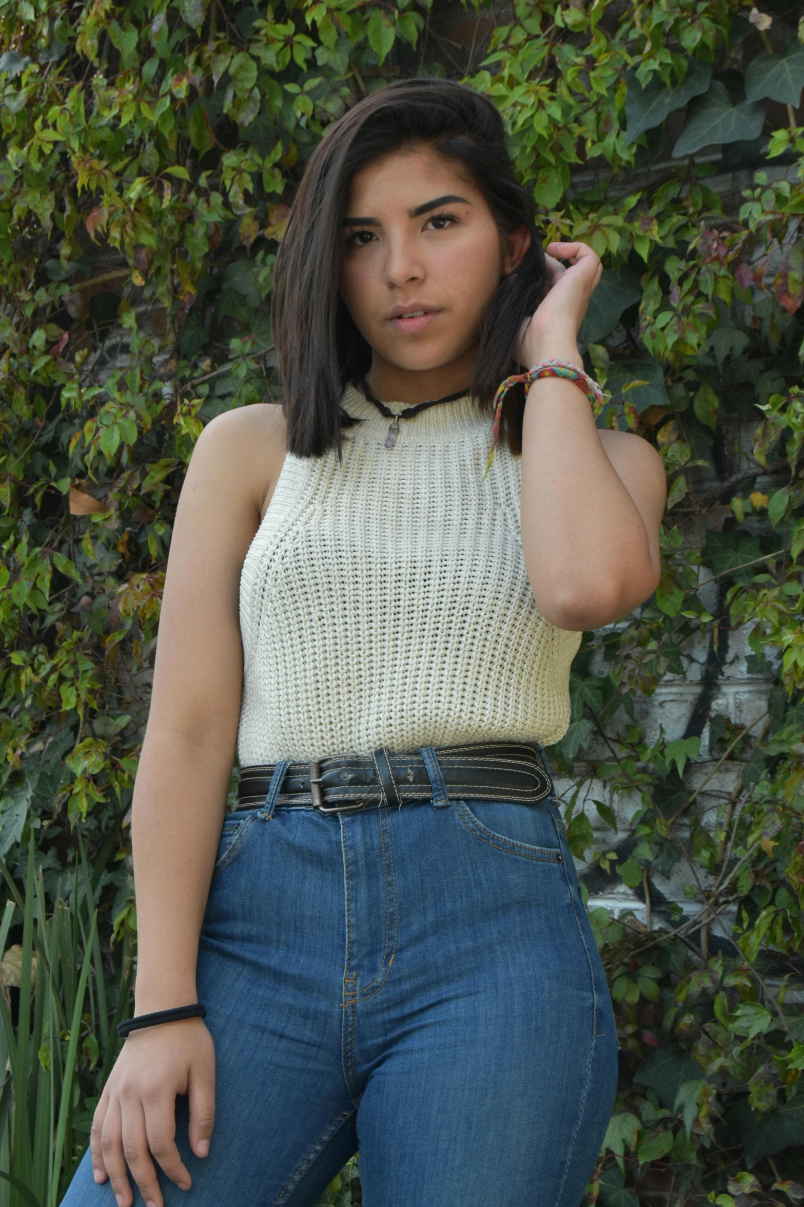 a woman is leaning up against a bush