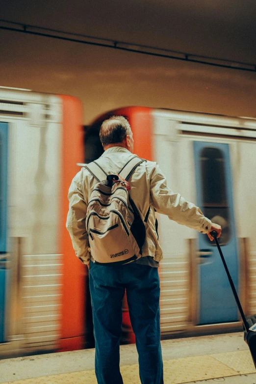 man at a train station pulling luggage and looking out the window