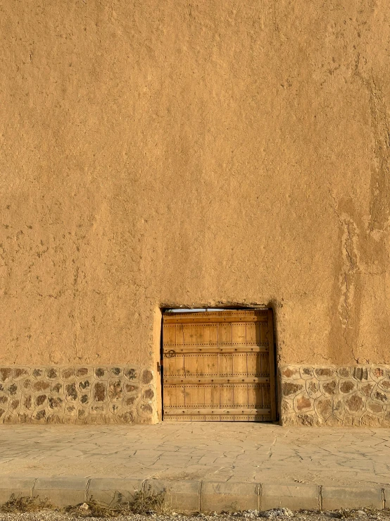 a door with a bench on a sidewalk in front of a wall