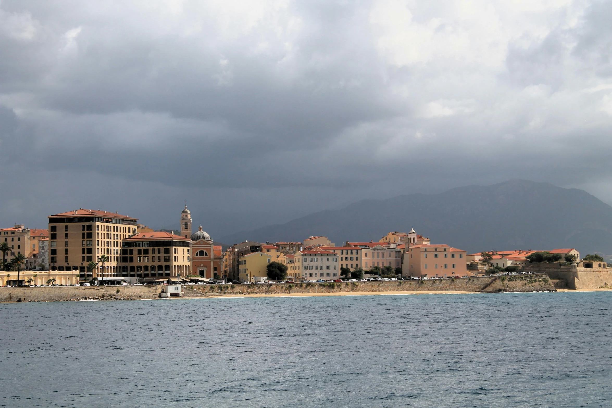 some buildings with mountains and the ocean in the background