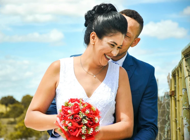 bride and groom with flowers against blue sky