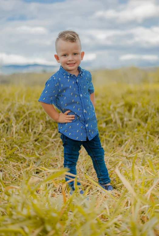 a small boy standing on top of a grass covered field