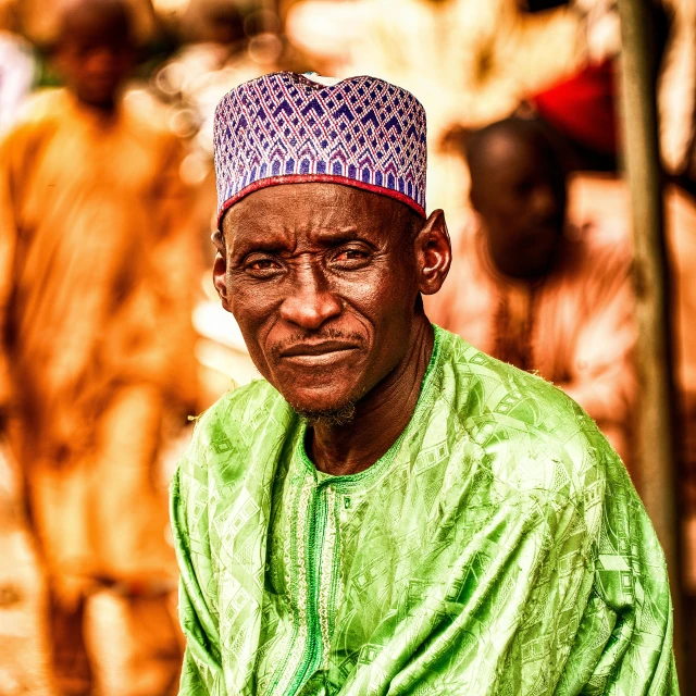 an older man with a bright colored hat in front of a group of people