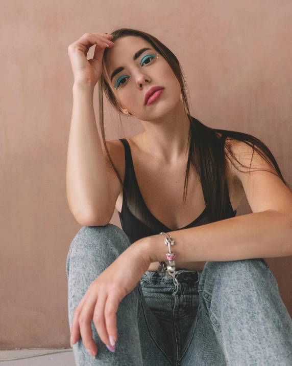 a beautiful young woman sitting down with her arm resting against her face