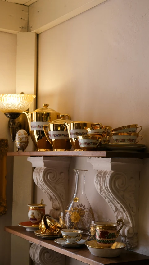 gold decorations, wine glasses, vases and mirror on a shelf