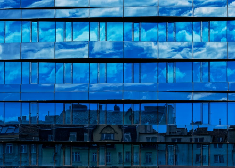 the sky reflected in the windows of another skyscr