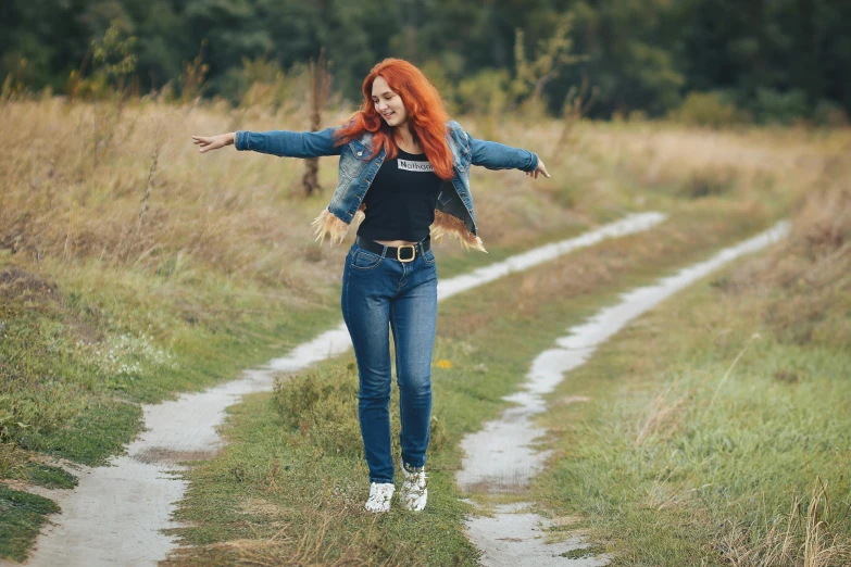 young woman with her arms outstretched walking down a trail