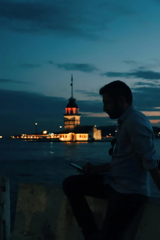 a man sitting on a ledge looking at a cell phone