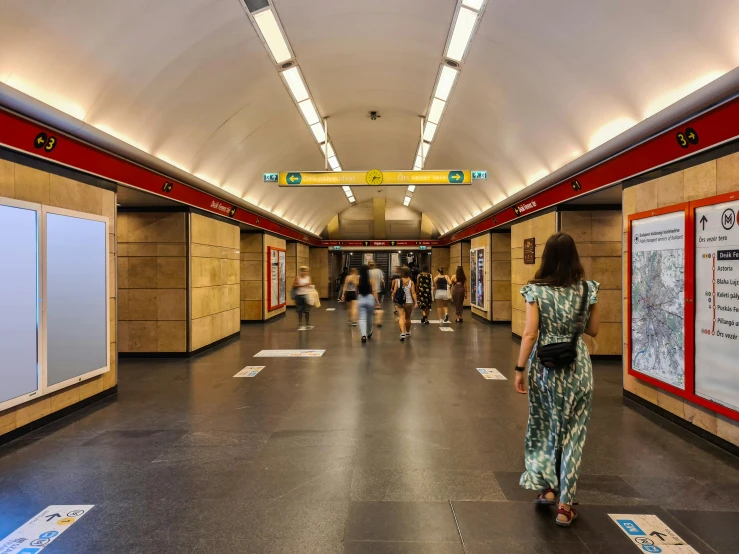 a woman walks down a large hallway past posters