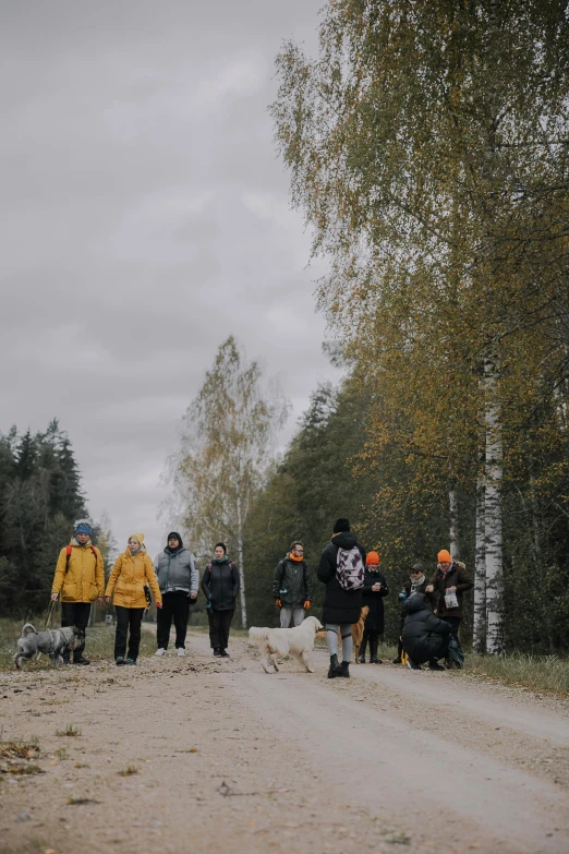 several people standing on a dirt road next to trees