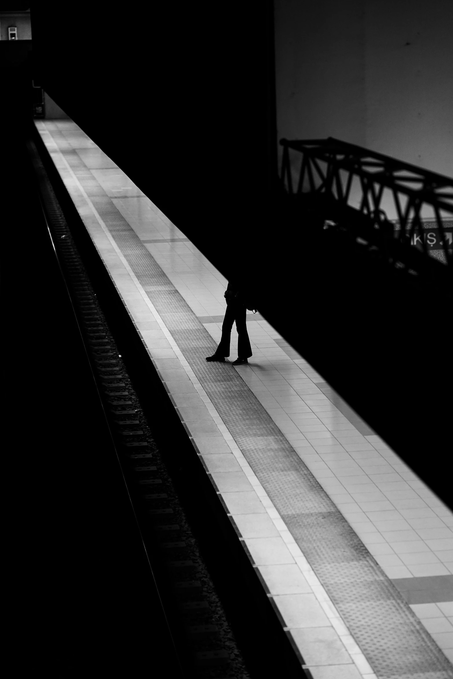 a person walking down a sidewalk next to a train track
