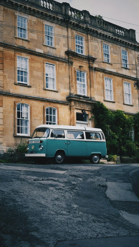 an old, classic style vw van sitting in front of a large stone building