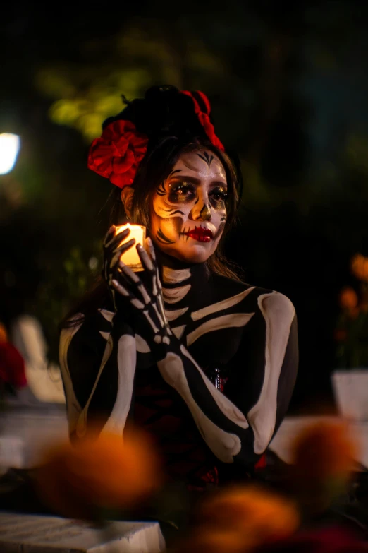 a lady in makeup holds a candle with her hands