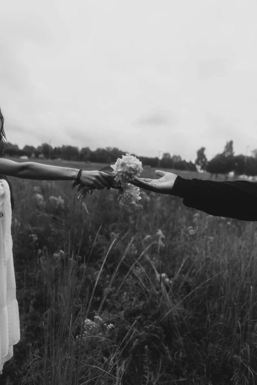 two people are holding hands in a field