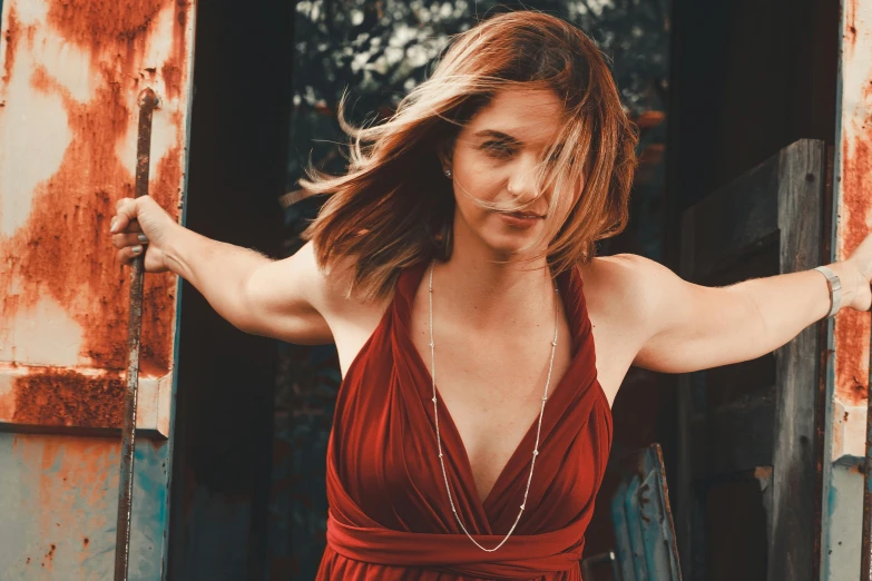 a woman wearing a red top, posing in front of an open door