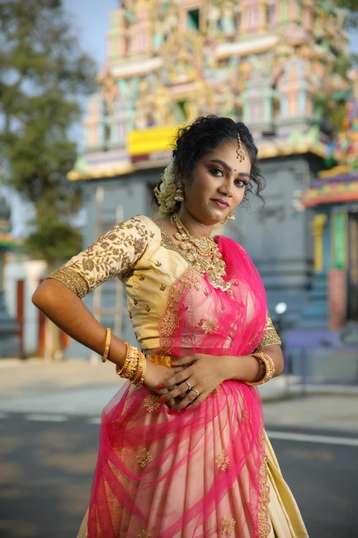 a beautiful woman dressed in a pink and gold colored blouse with a yellow shawl, wearing a yellow and pink saree