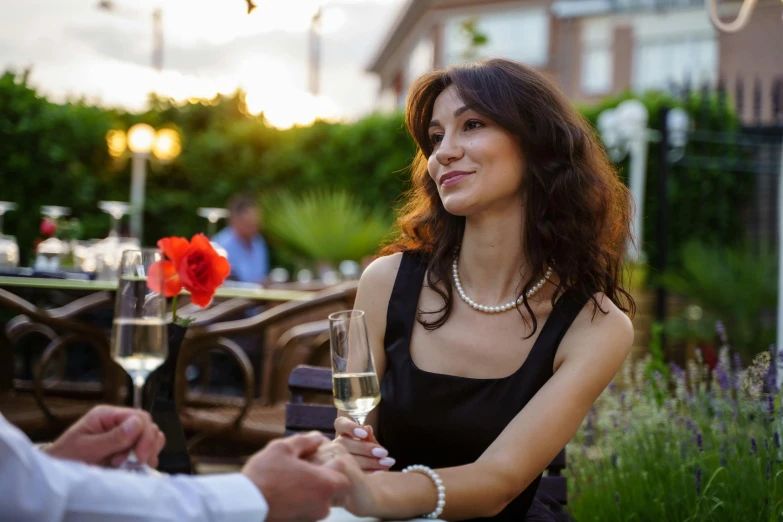 a beautiful woman sitting outside at a table and shaking hands