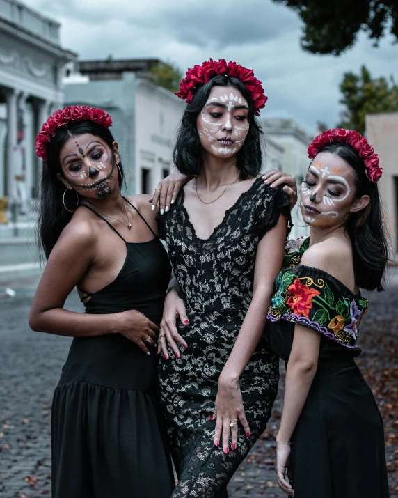 three women pose together with face painted