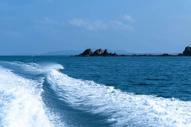 water waves in front of some rocks and blue skies