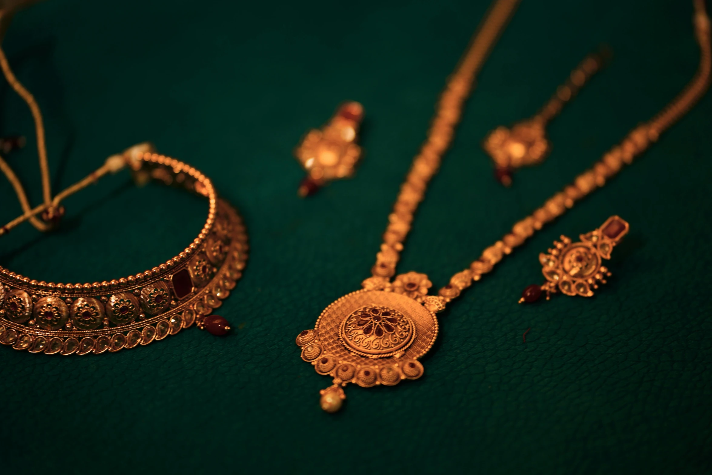 golden jewellery including earrings and rings sit on a green surface