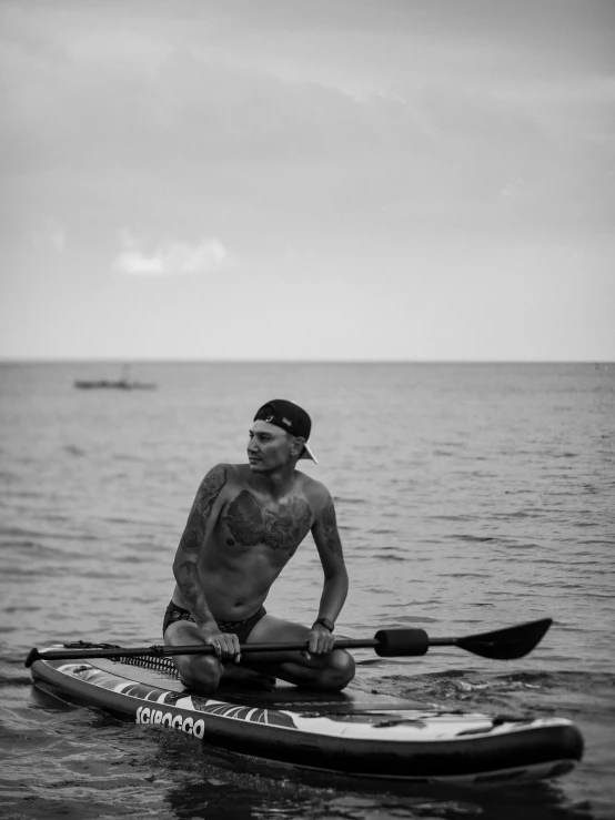 man sitting on his surf board next to the water