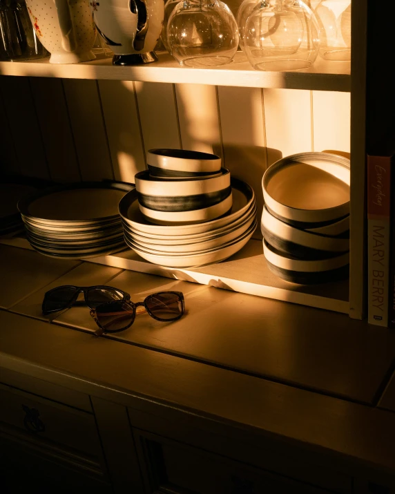 some plates are sitting on the shelf by the window
