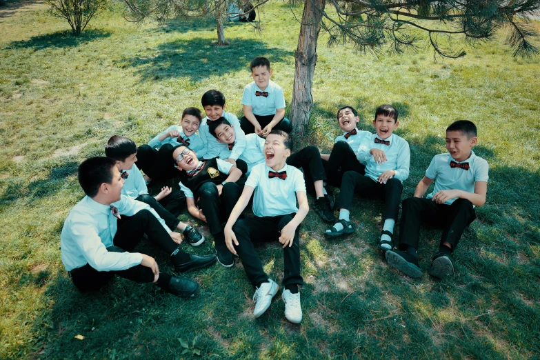 a bunch of little boys that are sitting under a tree