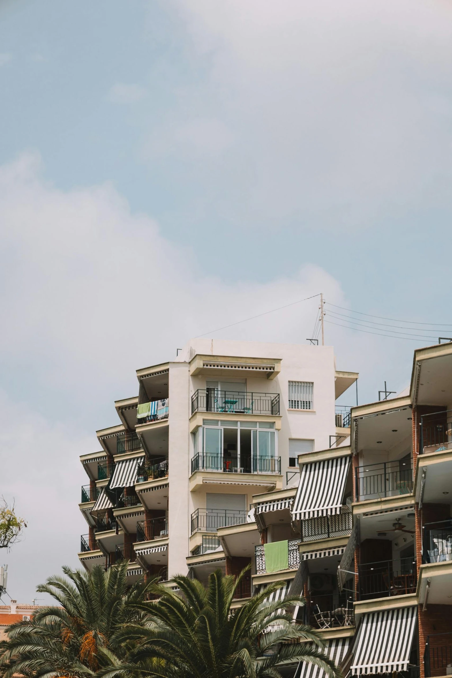 buildings with balconies and plants in front of the sky