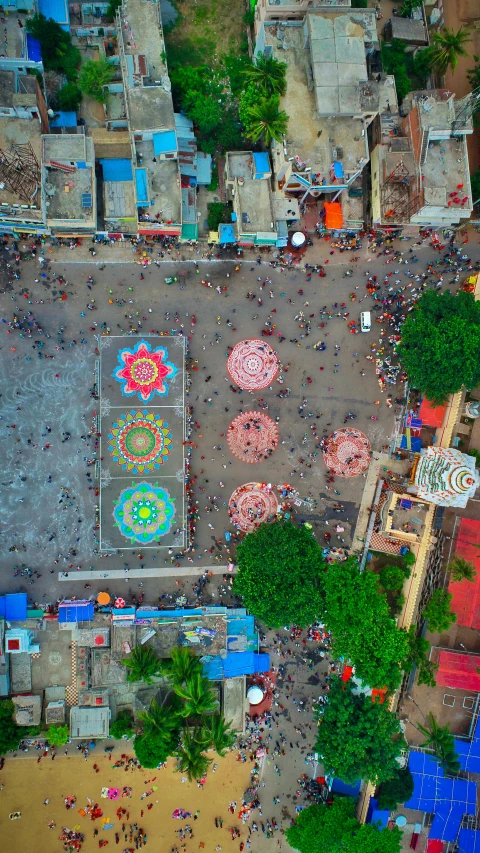 people are gathered in a square, including umbrellas