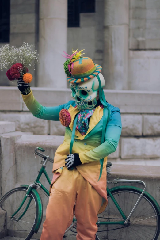 skeleton in green wig sitting on bicycle and holding flowers