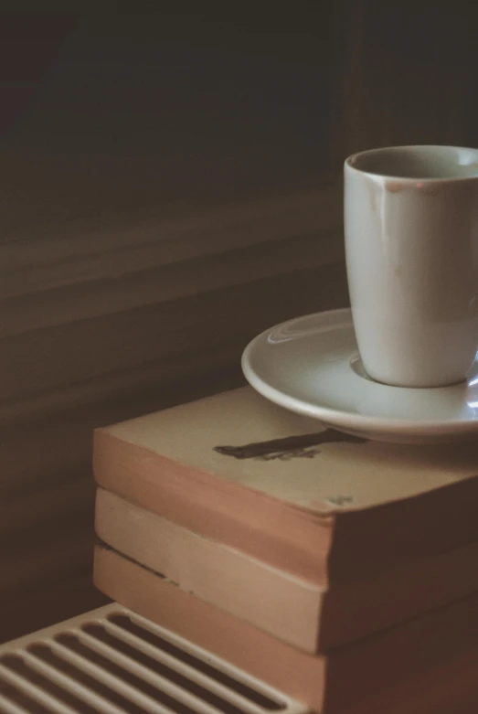 a table topped with a pile of books and a cup