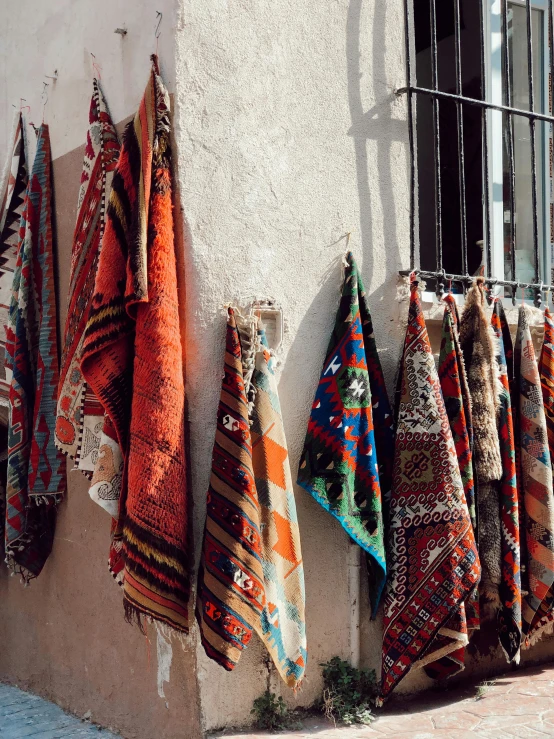 several colorfully colored towels hanging on the outside wall of a building