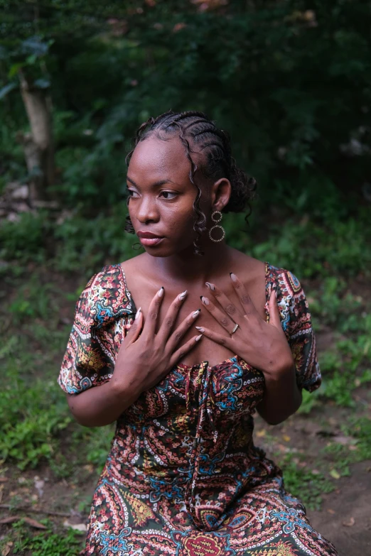 a woman with her hands crossed, sitting in the grass