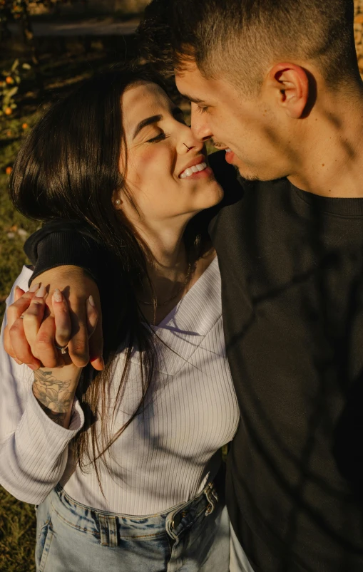 a couple holds their hands over their shoulders while leaning on a fence